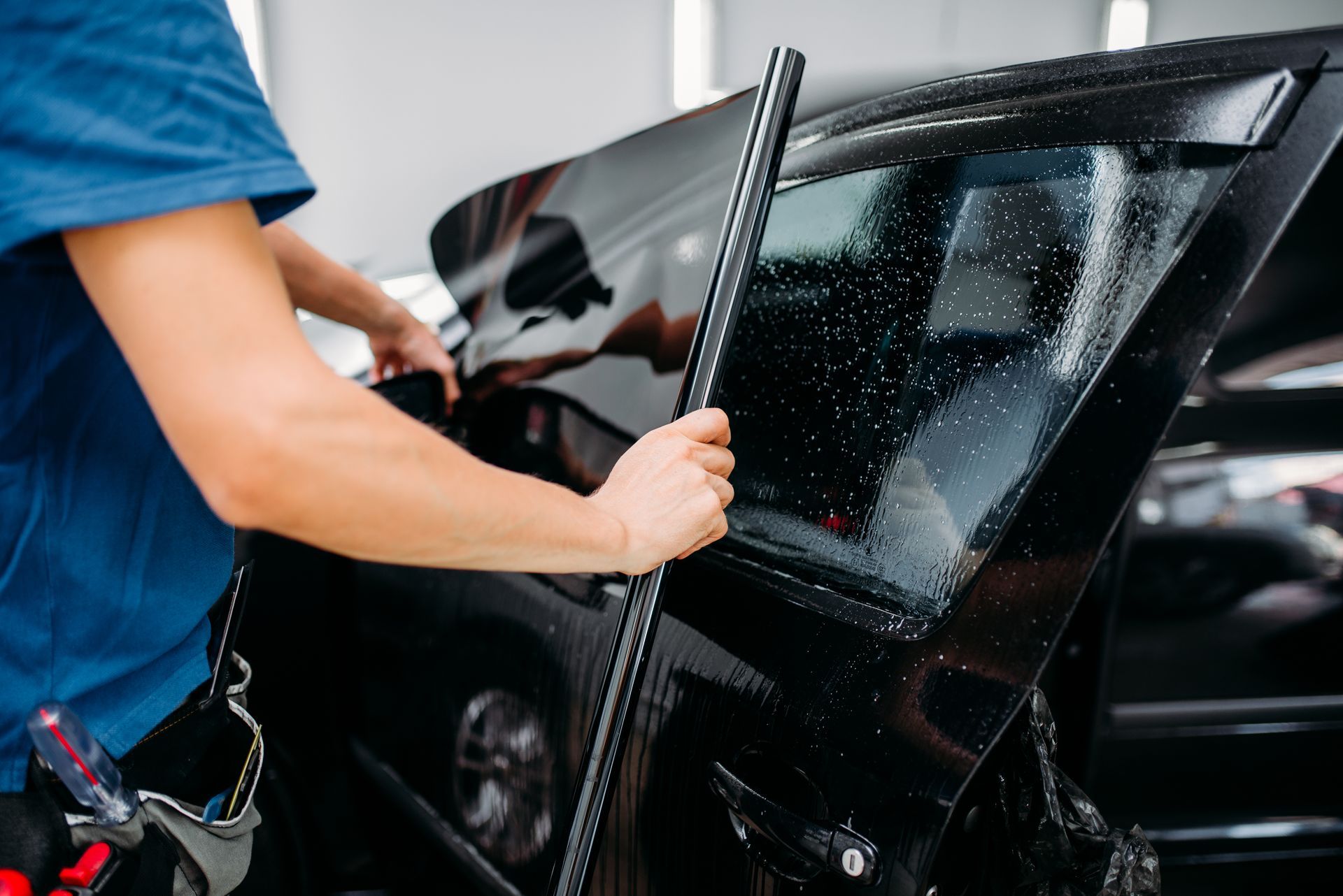 Technician installing window tint on a vehicle